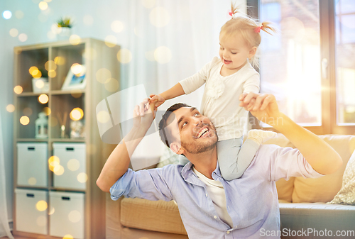 Image of father riding little baby daughter on neck at home