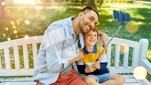 Image of father and son taking selfie with phone at park