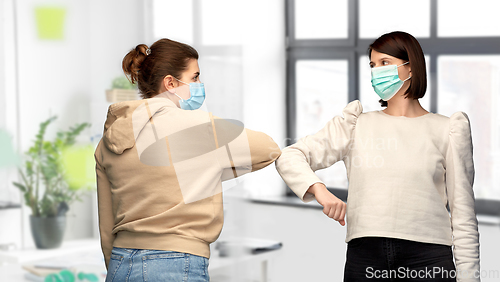 Image of women in masks making elbow bump greeting gesture