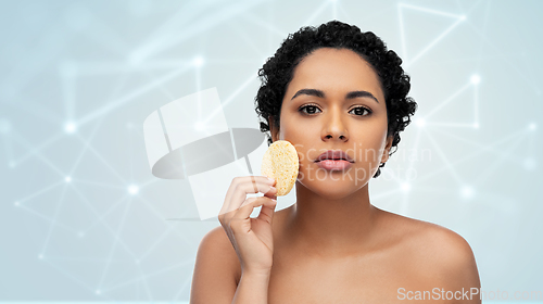 Image of young woman cleaning face with exfoliating sponge