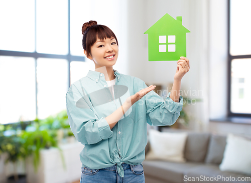 Image of smiling asian woman holding green house