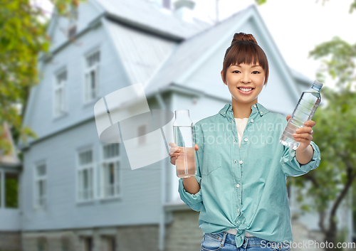 Image of asian woman with plastic and glass bottle of water