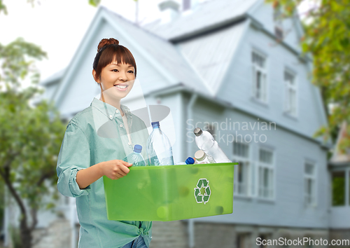 Image of smiling young asian woman sorting plastic waste