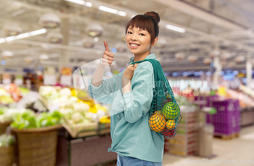 Image of happy asian woman with food in reusable string bag