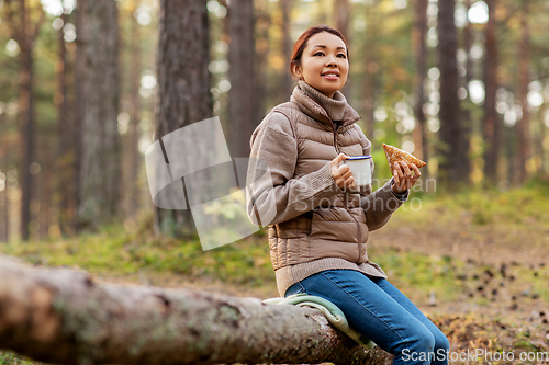 Image of woman drinking tea and eating sandwich in forest