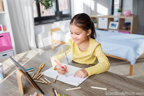 Image of little girl drawing with coloring pencils at home