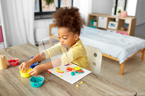 Image of little girl with modeling clay playing at home