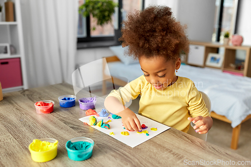 Image of little girl with modeling clay playing at home