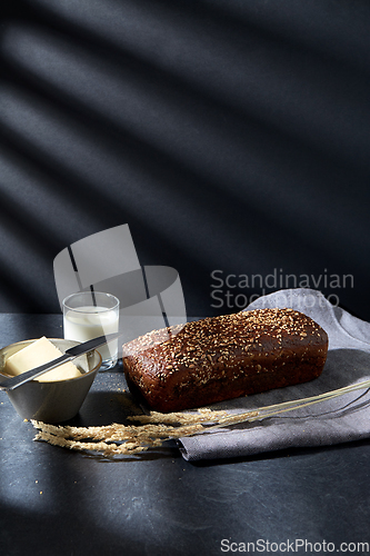 Image of close up of bread, butter, knife and glass of milk