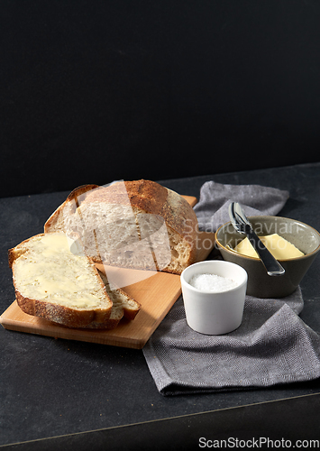 Image of close up of bread, butter, knife and salt on towel