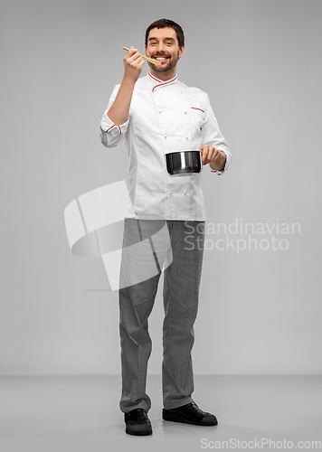 Image of happy smiling male chef with saucepan tasting food