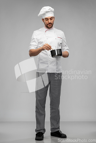 Image of male chef in toque with saucepan cooking food