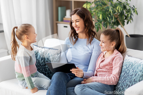 Image of happy mother and daughters with tablet pc at home