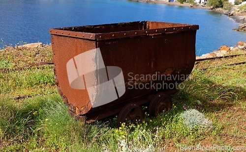 Image of Old rusty coal tub or trolley on tracks, on the sea cliff in Megalo Livadi village, Serifos island, Greece