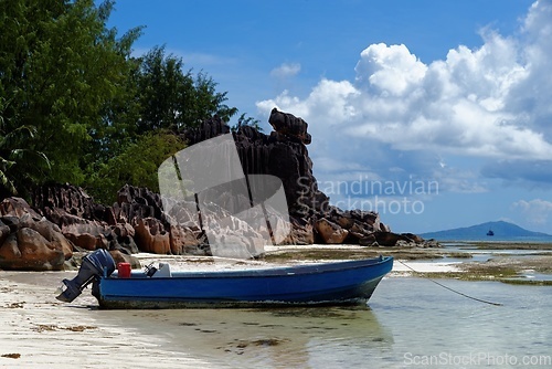 Image of Motor boat at the beach on Curieuse Island, Seychelles, with lava stone rocks and lush vegetation