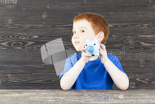 Image of boy checks his piggy bank