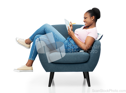 Image of happy young woman in armchair writing to notebook