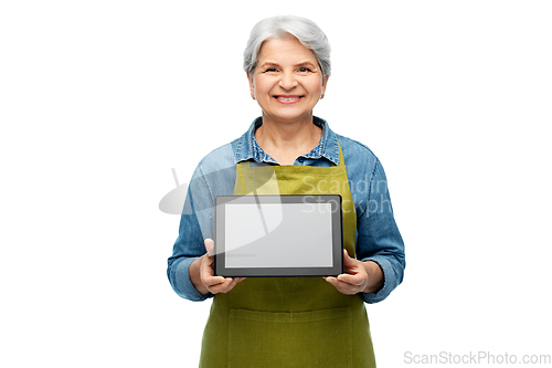 Image of happy senior woman in garden apron with tablet pc