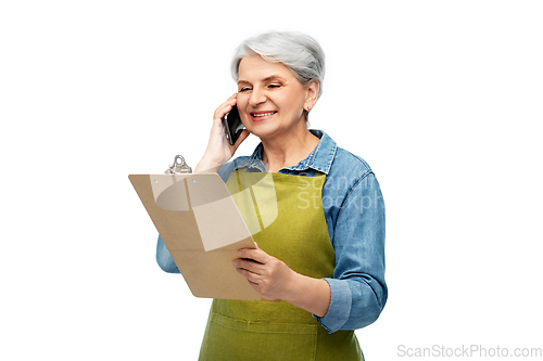 Image of old female gardener with clipboard calls on phone