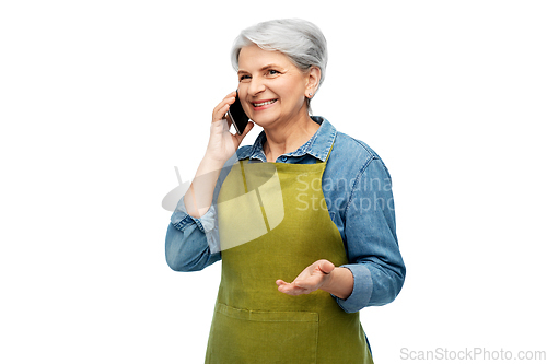 Image of senior woman in garden apron calling on smartphone