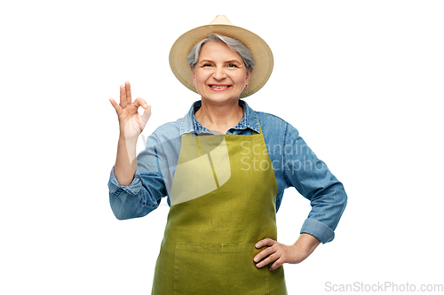 Image of senior woman in garden apron showing ok gesture