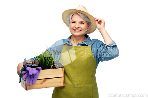 Image of smiling senior woman with garden tools in box