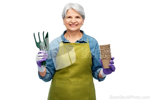 Image of old woman in apron with pots and garden tools