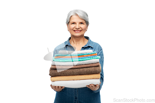 Image of smiling senior woman with clean bath towels