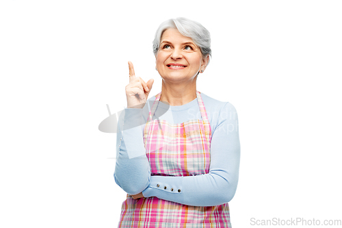 Image of smiling senior woman in apron pointing finger up