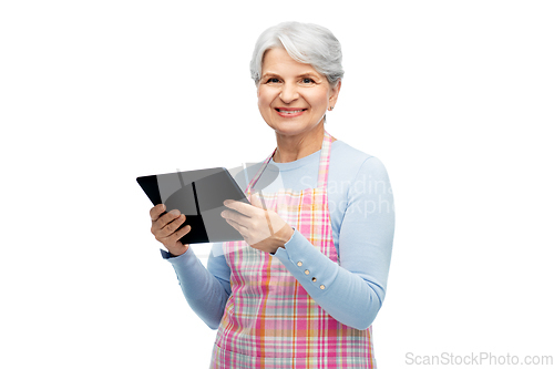 Image of smiling senior woman in apron with tablet computer