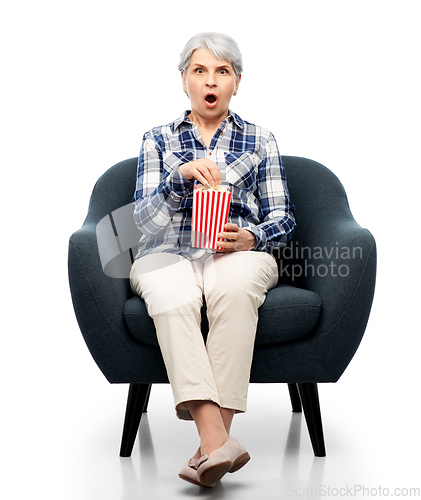 Image of senior woman eating popcorn sitting in armchair