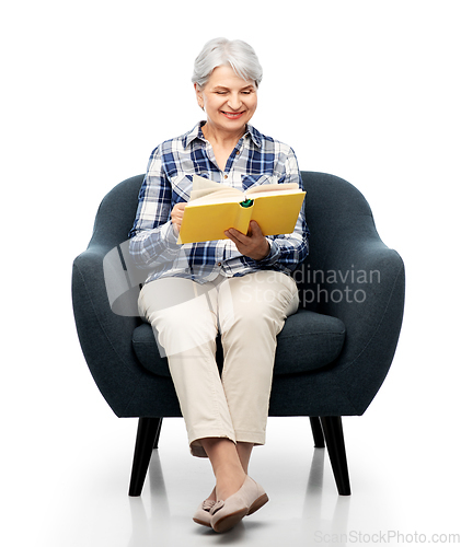 Image of senior woman reading book sitting in armchair