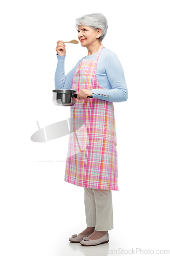 Image of senior woman in apron with pot cooking food