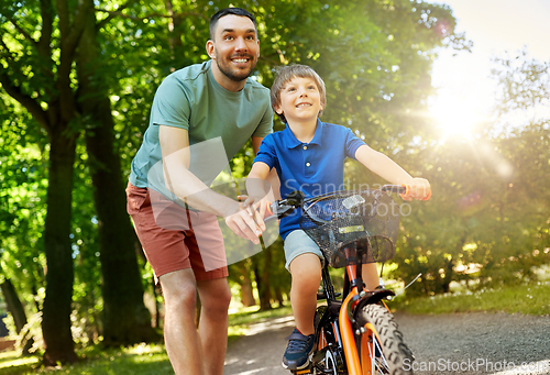 Image of father teaching little son to ride bicycle at park