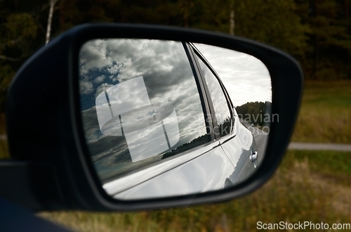 Image of clouds are reflected in the car's rearview mirror