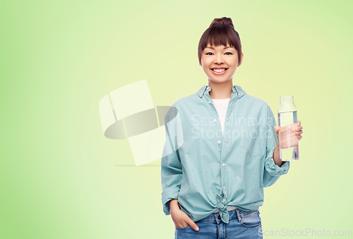 Image of happy asian woman holding glass bottle with water