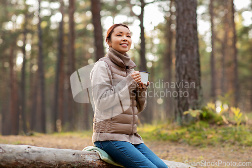 Image of asian woman with mug drinking tea in forest