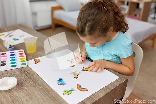 Image of little girl painting wooden items at home