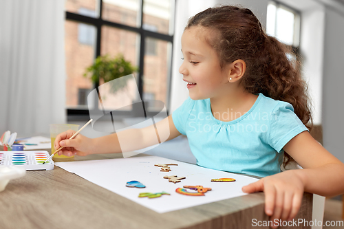 Image of little girl painting wooden items at home