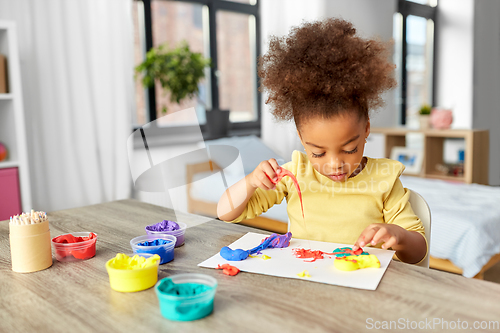 Image of little girl with modeling clay playing at home