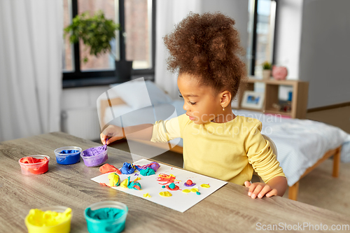 Image of little girl with modeling clay playing at home