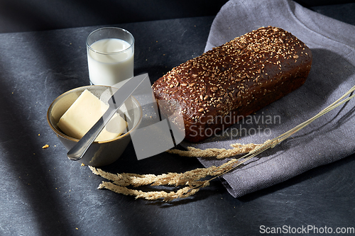 Image of close up of bread, butter, knife and glass of milk