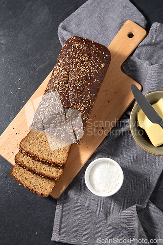 Image of close up of bread, butter, knife and salt on towel