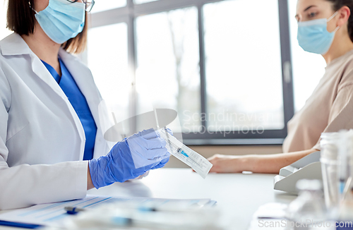 Image of female doctor with syringe and patient at hospital