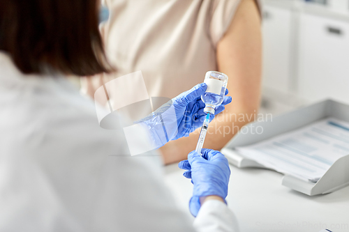 Image of female doctor with syringe vaccinating patient