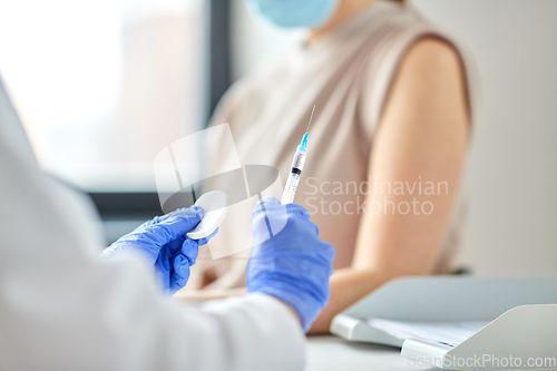 Image of female doctor with syringe vaccinating patient