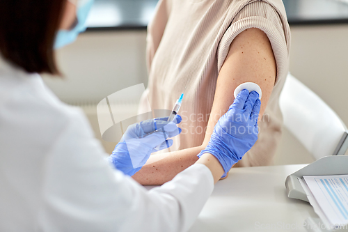 Image of female doctor with syringe vaccinating patient