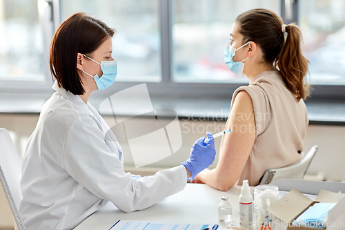 Image of female doctor with syringe vaccinating patient