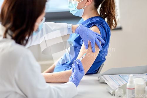 Image of doctor with syringe vaccinating medical worker