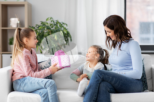 Image of girl giving present to younger sister at home